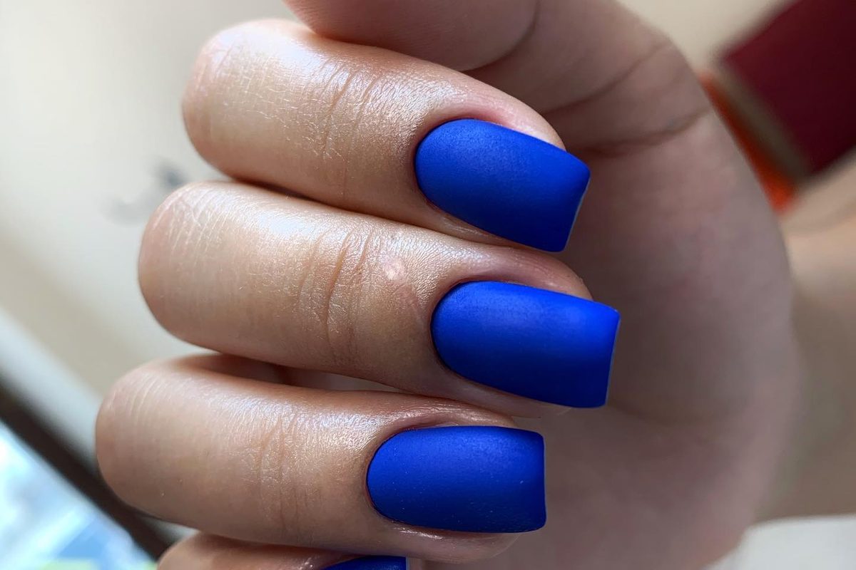 Matte cobalt-blue gel manicure with a clean cuticle line