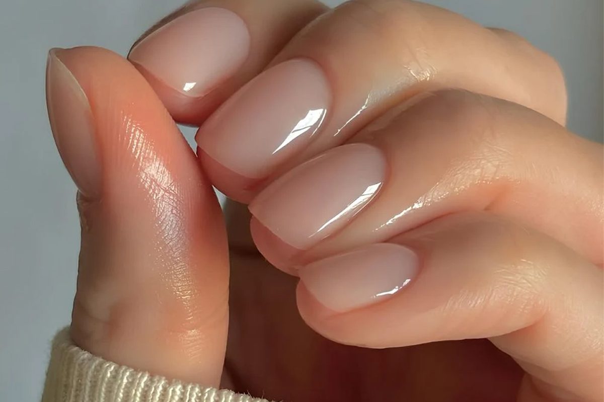 Glossy nude gel manicure with polish sitting close to the cuticle